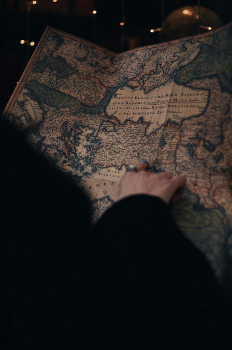 Mao apontando um mapa antigo europeu durante pesquisa da origem geografica de um sobrenome