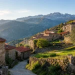 Vila de casas de pedra em encosta verde da Serra da Estrela, em Portugal, com telhados de telha e muros de pedra seca, ao amanhecer